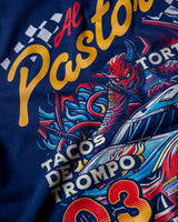 Taco Gear Al Pastor Racing t-shirt with colorful taco-themed racecar graphic, devil driver, and bold “Tacos de Trompo” and “Racing” text on navy and red tees.
